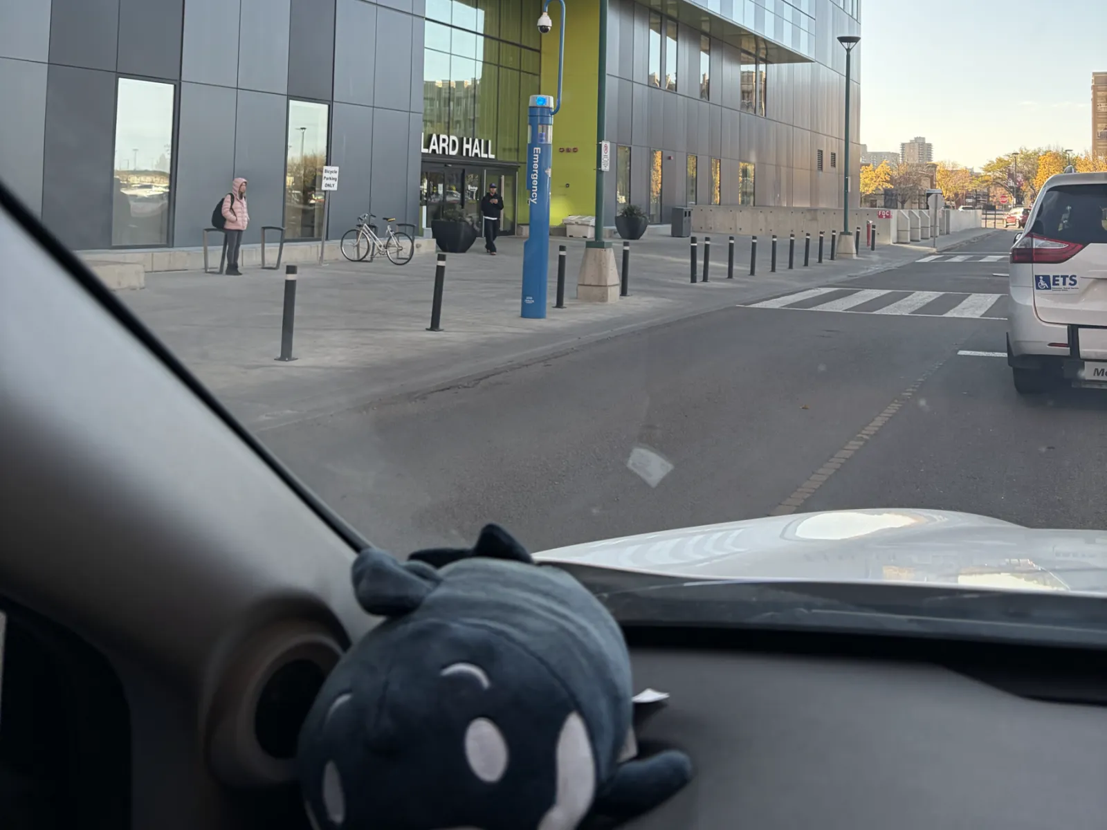 Allard Hall at MacEwan University, seen through a car windshield with a plush toy on the dashboard